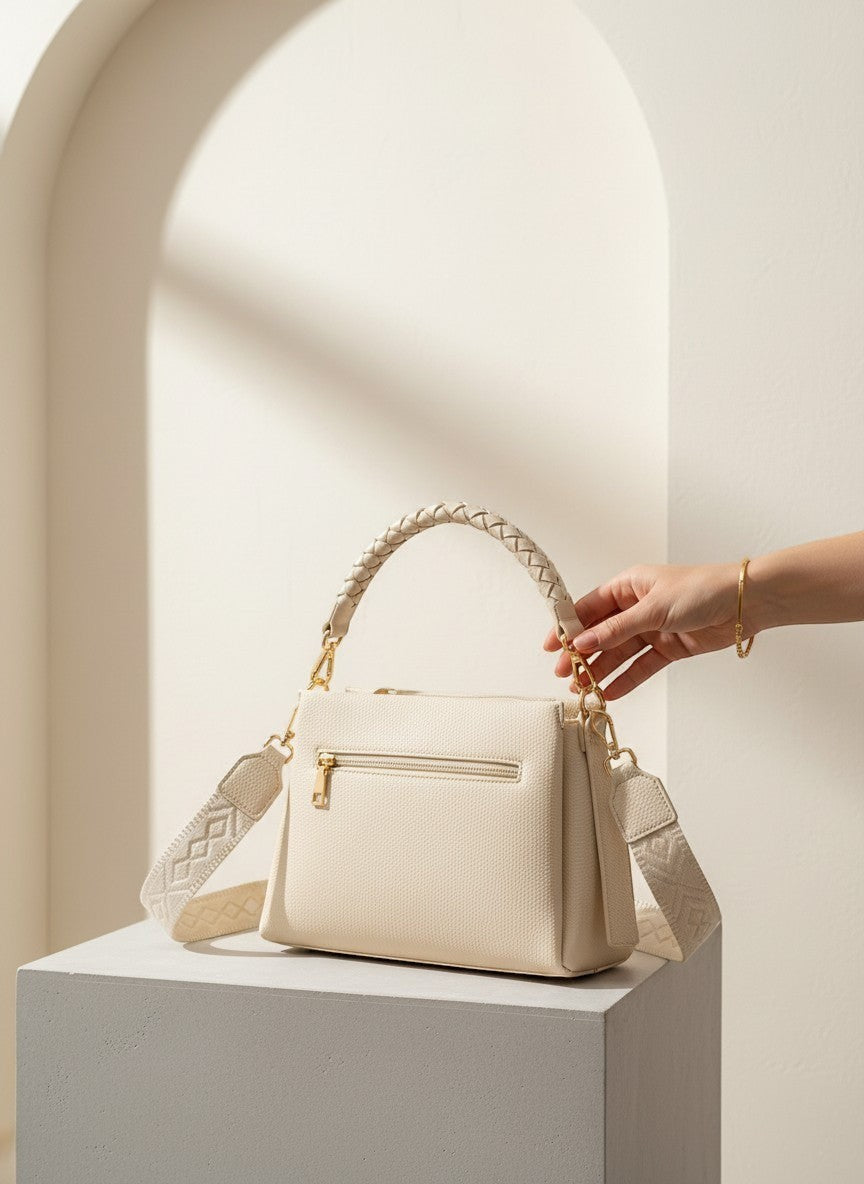 Структурирана бежова чанта от еко кожа на Benny Boutique с оплетена дръжка и шарена презрамка върху постамент.