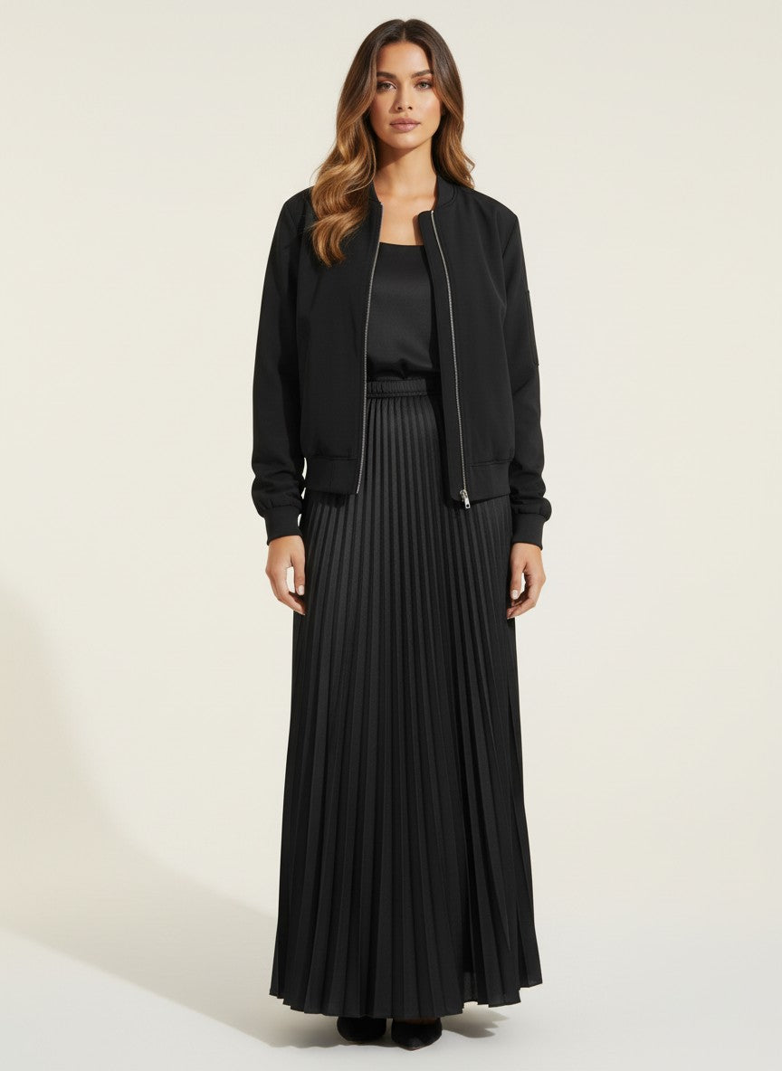 Черно яке тип „бомбър“ от Benny Boutique със закопчаване с цип и рипсени маншети, носено от модел в комбинация с подходяща плисирана пола.