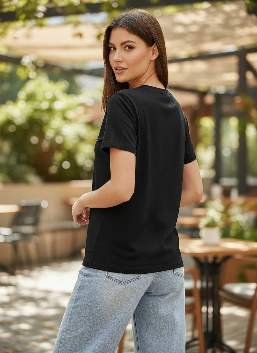 Benny Boutique черна памучна тениска с графичен принт и надпис, носена от жена със светлосини дънки.