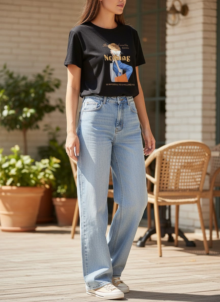 Benny Boutique черна памучна тениска с графичен принт и надпис, носена от жена със светлосини дънки.