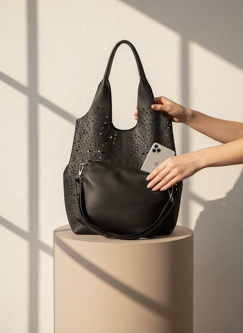 Черен шопър от еко кожа с лазерно изрязване на Benny Boutique с подходящ вътрешен несесер върху постамент.