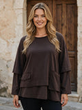 Многослойна кафява блуза от Benny Boutique с дълги ръкави, предни джобове и необработени краища, облечена на усмихната руса манекенка.