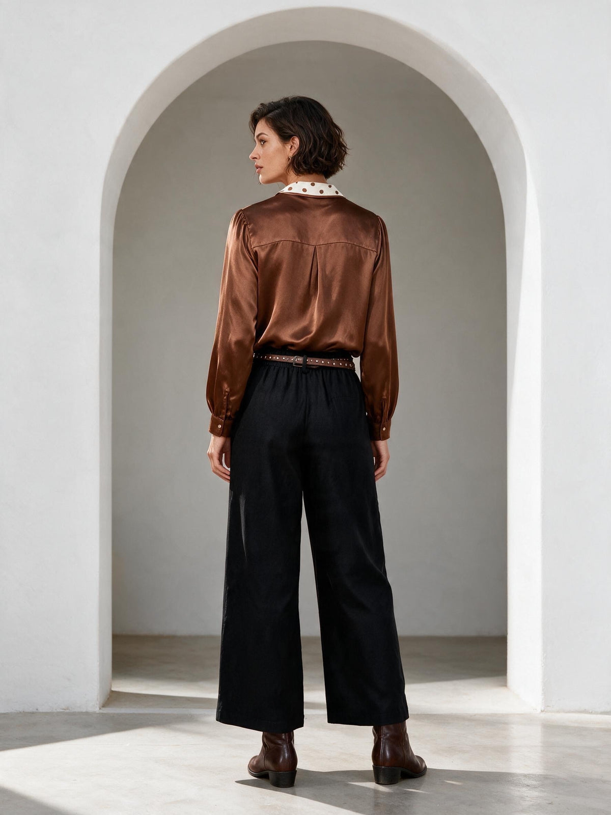 Кафява сатенена блуза Benny Boutique с яка на точки и обемни ръкави, съчетана с черен панталон.