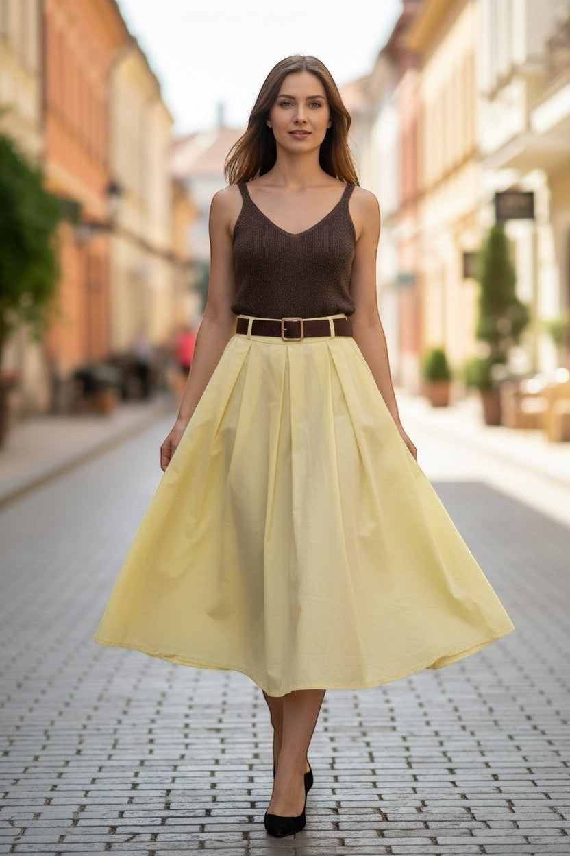 Кафяв блестящ топ от фино плетиво Benny Boutique, носен от жена с жълта миди пола на градска улица.