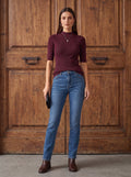 Бордо безшевна рипсена блуза Benny Boutique с къси ръкави и яка тип поло, съчетана със сини дънки пред дървена врата.