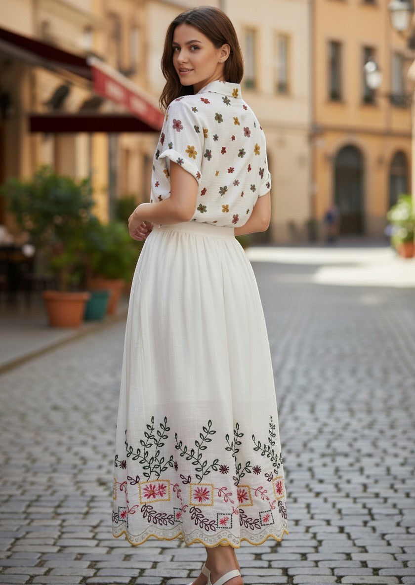 Benny Boutique бяла памучна миди пола с цветна фолклорна бродерия, стилизирана за летен бохо вид на градска улица.