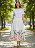 Benny Boutique бяла памучна миди пола с цветна фолклорна бродерия, стилизирана за летен бохо вид на градска улица.