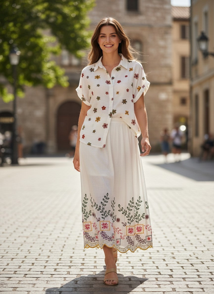 Benny Boutique бяла памучна миди пола с цветна фолклорна бродерия, стилизирана за летен бохо вид на градска улица.
