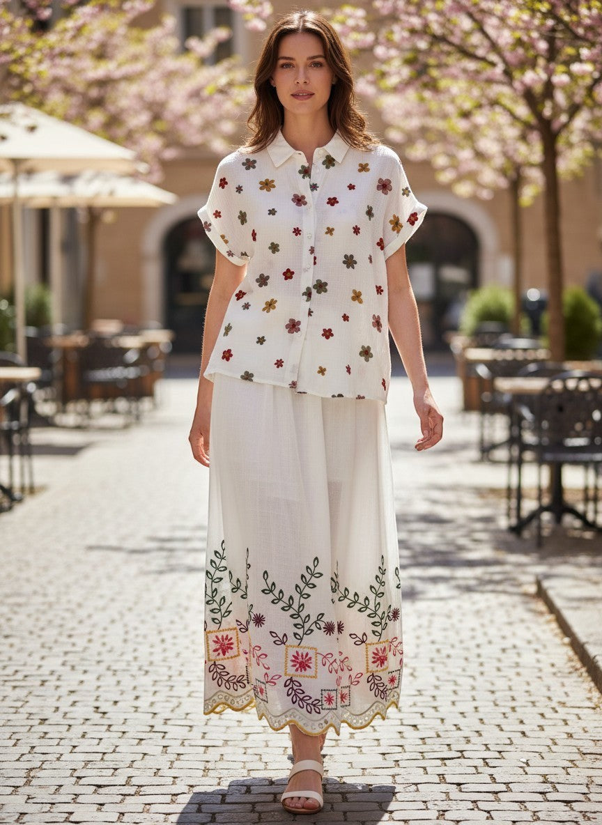 Benny Boutique бяла памучна лятна риза с цветна флорална бродерия и съчетана пола върху усмихнат модел.