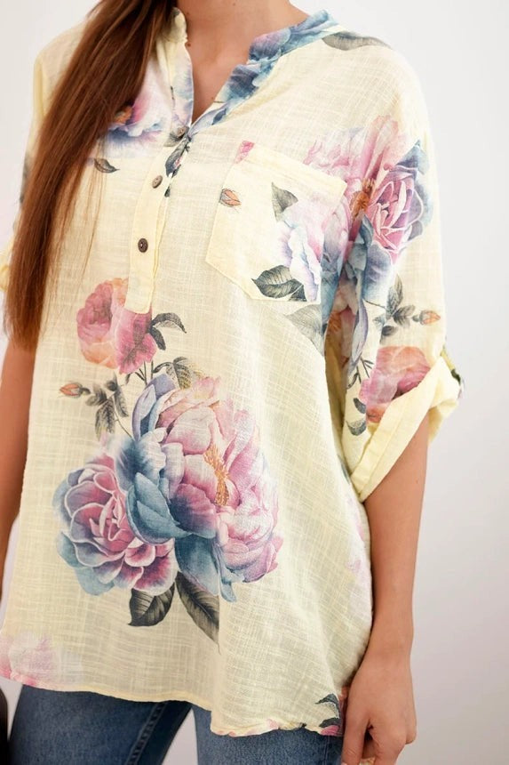 Benny Boutique пастелно жълта муселинова туника с регулиращи се ръкави и голям флорален принт в розово, синьо и лилаво.