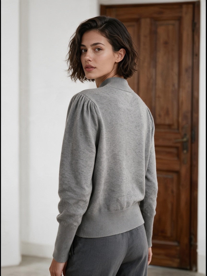 Сив пуловер от Benny Boutique с буфан ръкави, висока оребрена яка и деликатен блясък, облечен от жена.