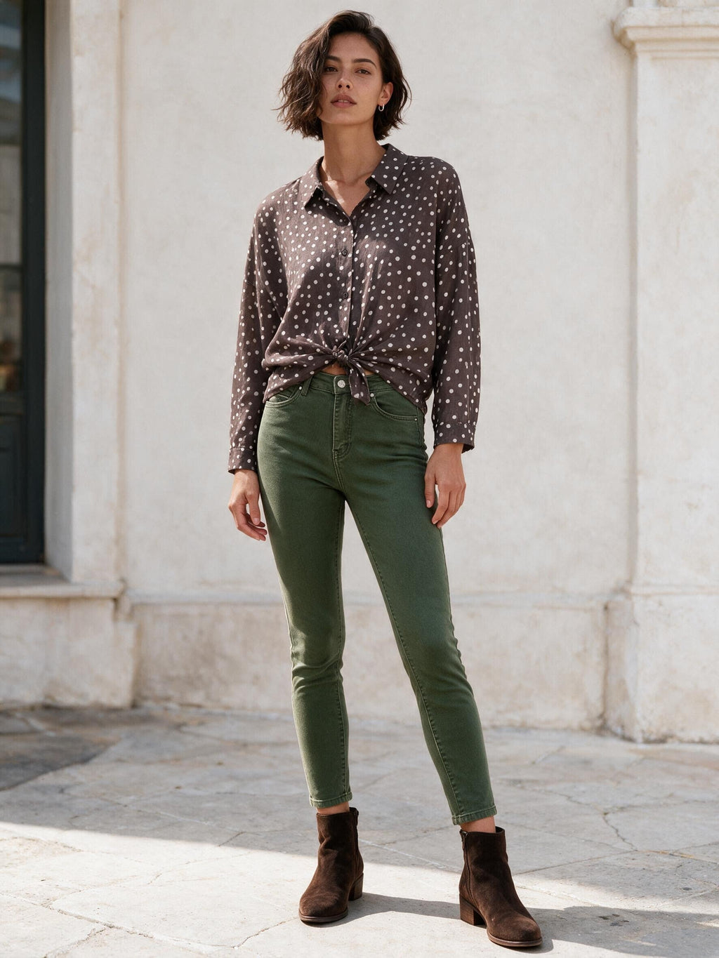 Маслиненозелени дънки Benny Boutique с прилепнала кройка и висока талия, облечени от жена в блуза на точки и кафяви боти до глезена.