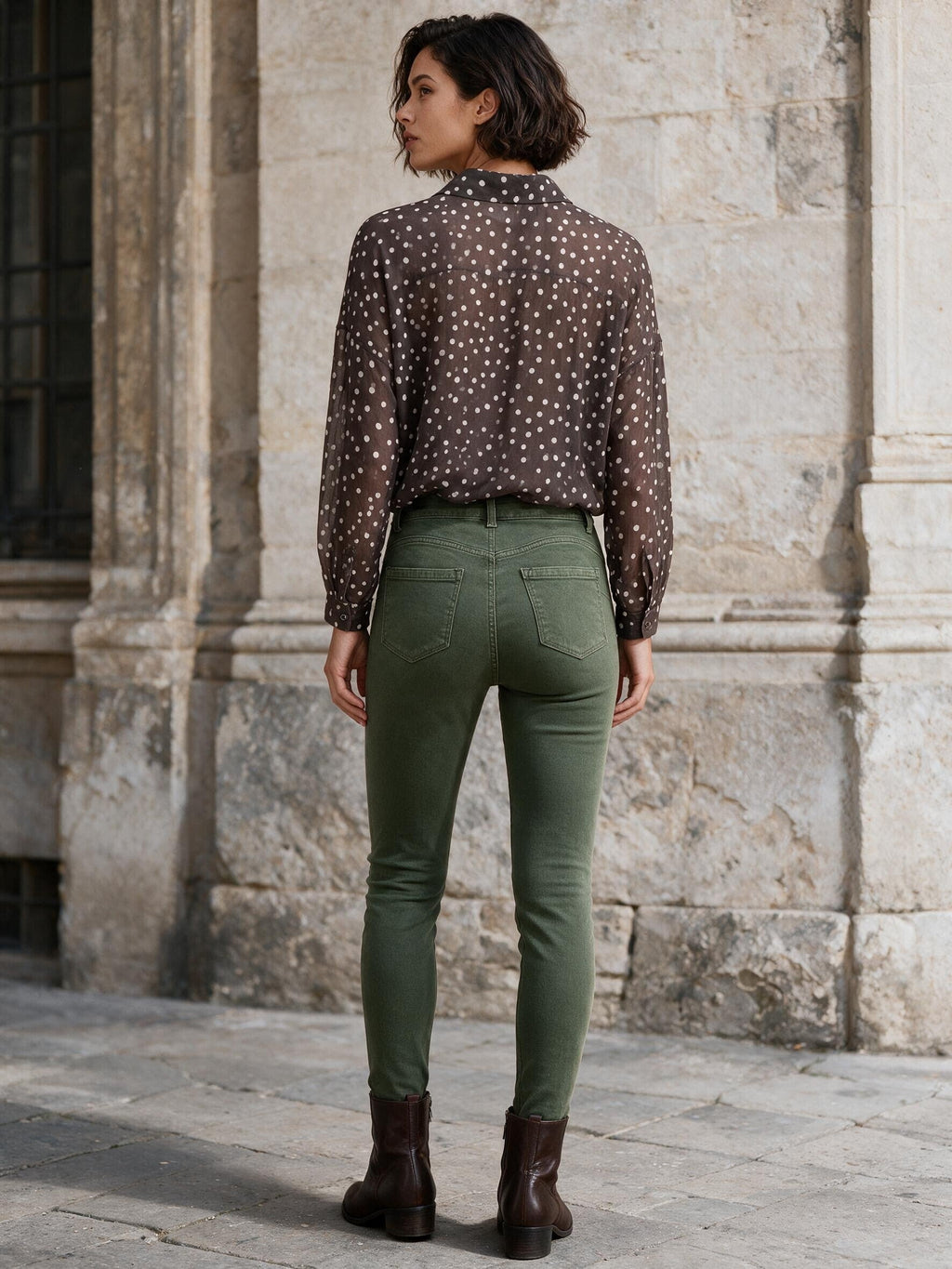 Маслиненозелени дънки Benny Boutique с прилепнала кройка и висока талия, облечени от жена с блуза на точки и кафяви боти до глезена.