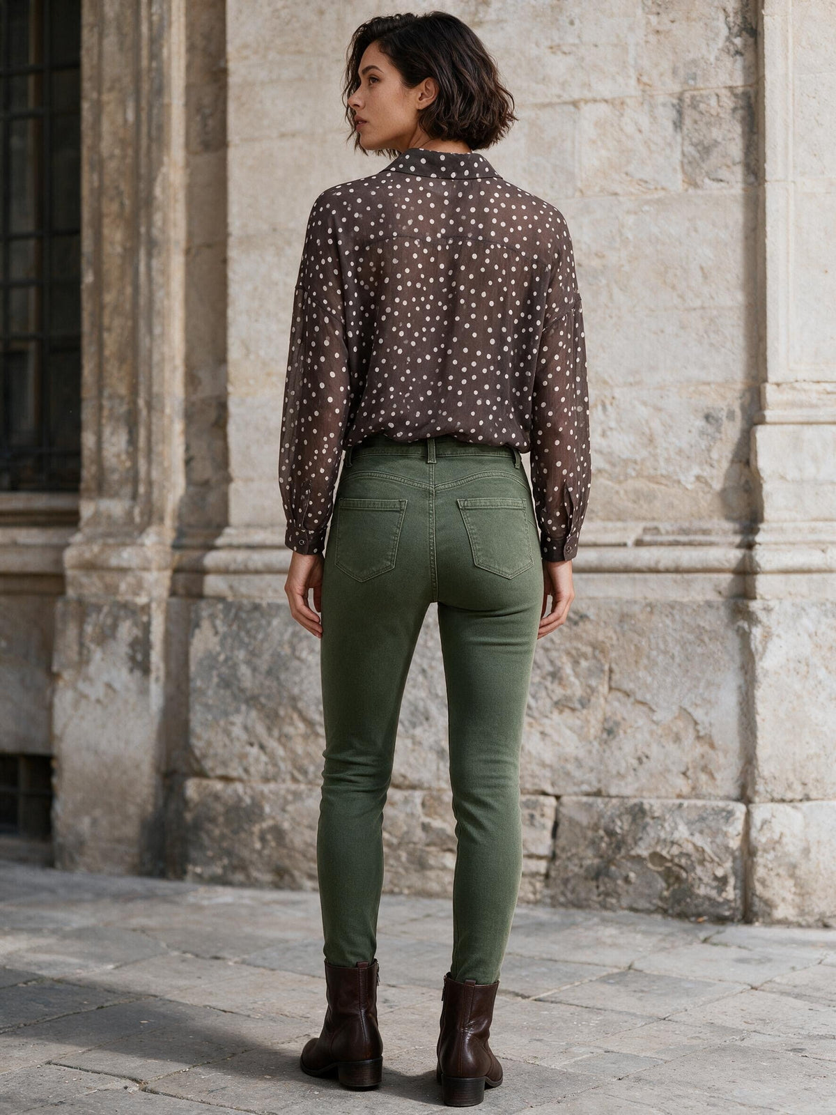 Маслиненозелени дънки Benny Boutique с прилепнала кройка и висока талия, облечени от жена с блуза на точки и кафяви боти до глезена.