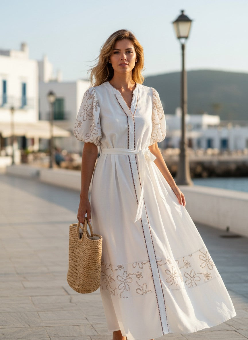 Бяла макси рокля Benny Boutique с бродирани буфан ръкави и връзка на талията, носена от жена на слънчева крайбрежна алея.
