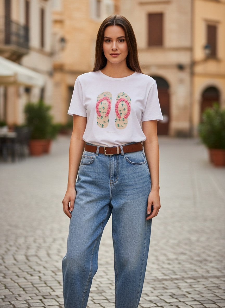 Benny Boutique бяла памучна тениска с розов принт на джапанки и релефни детайли. Моделът я носи със светли дънки.