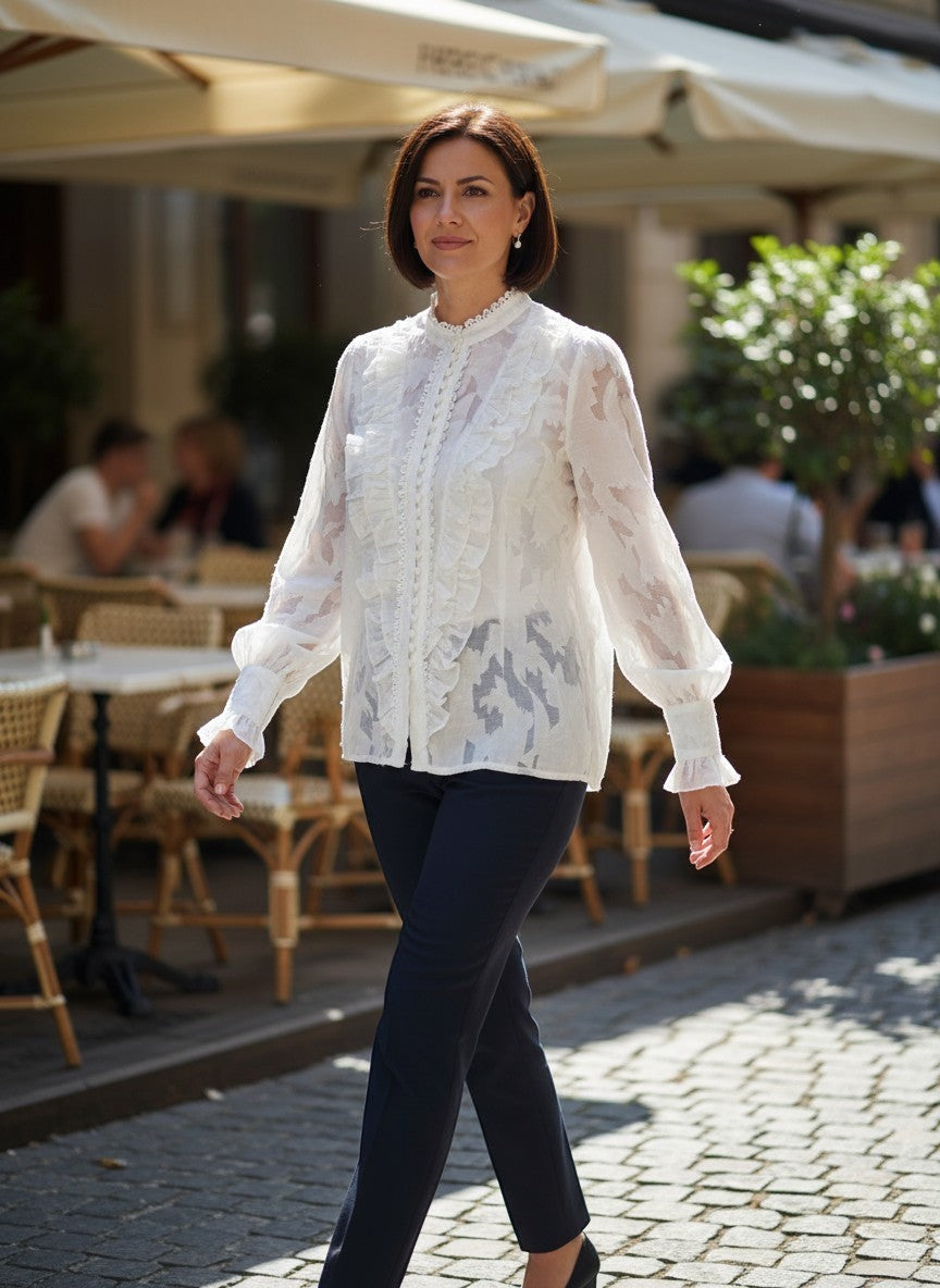 Benny Boutique бяла прозрачна блуза с флорален релеф, къдри и дълги ръкави, носена от жена на градска улица.