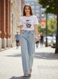 Benny Boutique бяла памучна тениска с графичен принт и надпис, съчетана със светлосини дънки с широк крачол.
