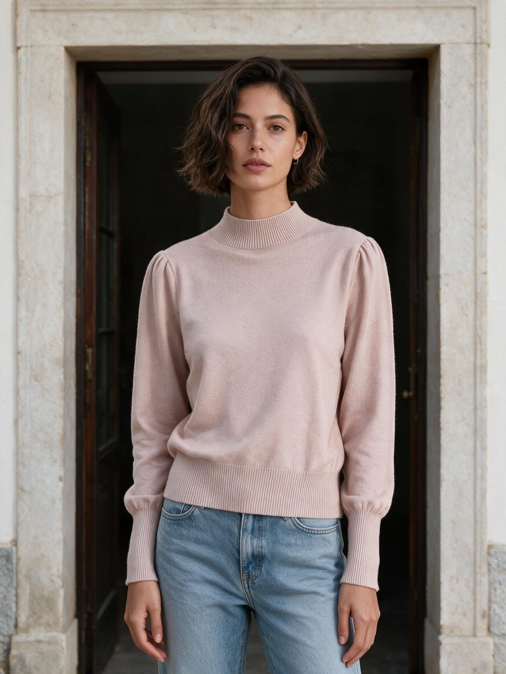 Пастеленорозов пуловер от Benny Boutique с буфан ръкави, висока оребрена яка и деликатен блясък, съчетан със сини дънки.